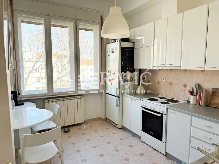 Small bright kitchen with white cabinets and a dining table by the window.