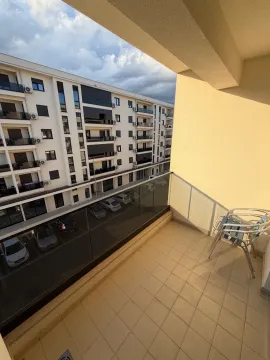 Small balcony with glass railing and chairs, overlooking the neighbouring building and parking lot. - image 6