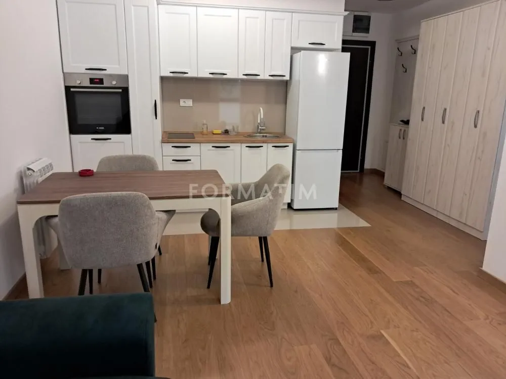 Kitchen with dining area equipped with white cabinetry and a wooden table.