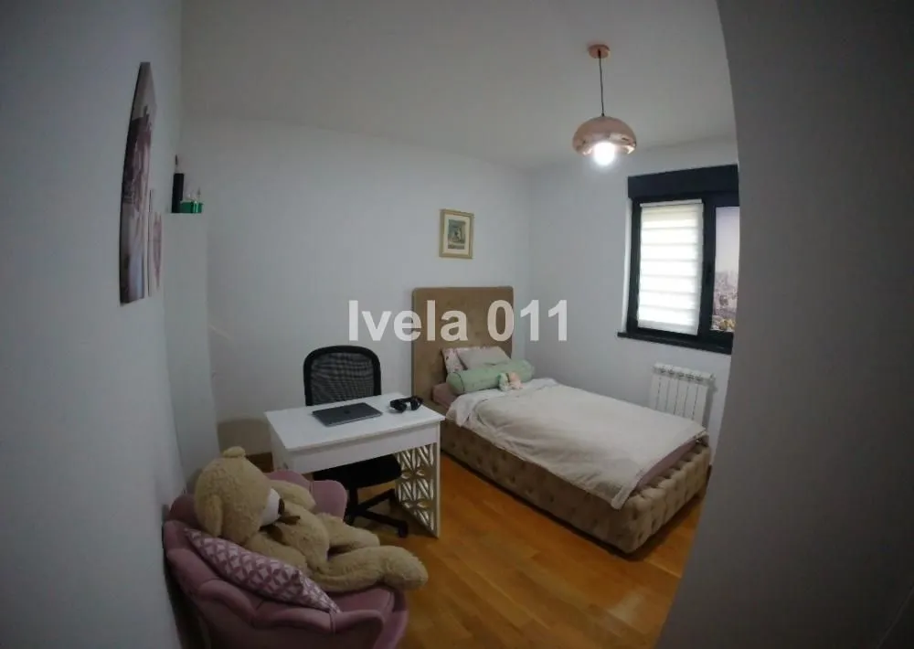 Dečja soba sa krevetom, radnim stolom i foteljom sa plišanim medvedićem.