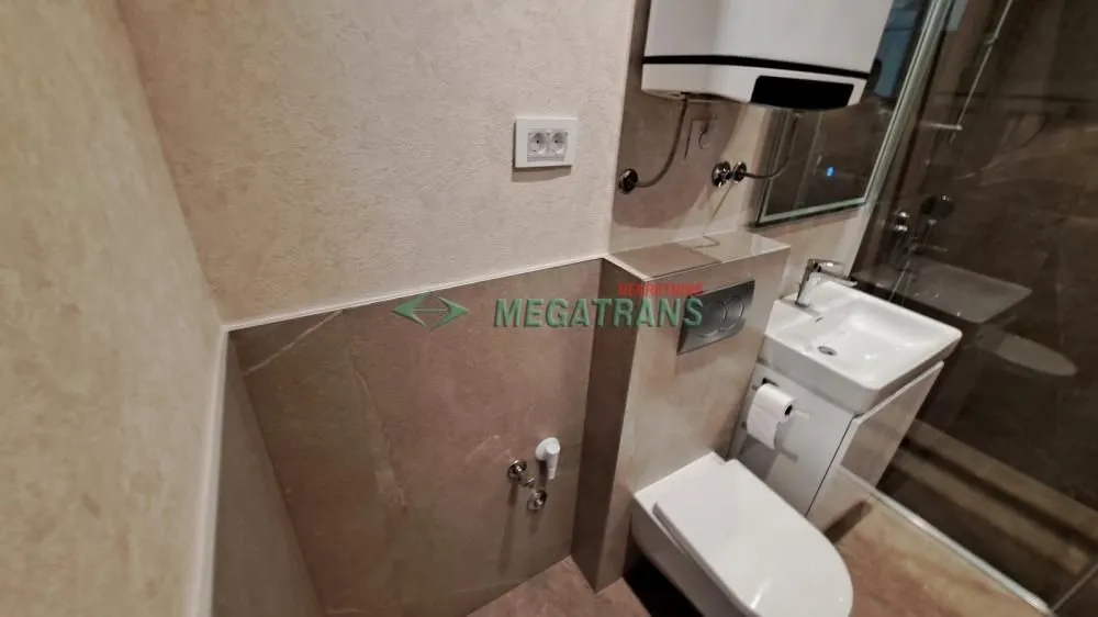 Pogled na kupatilo sa WC šoljom, umivaonikom i tuš kabinom.