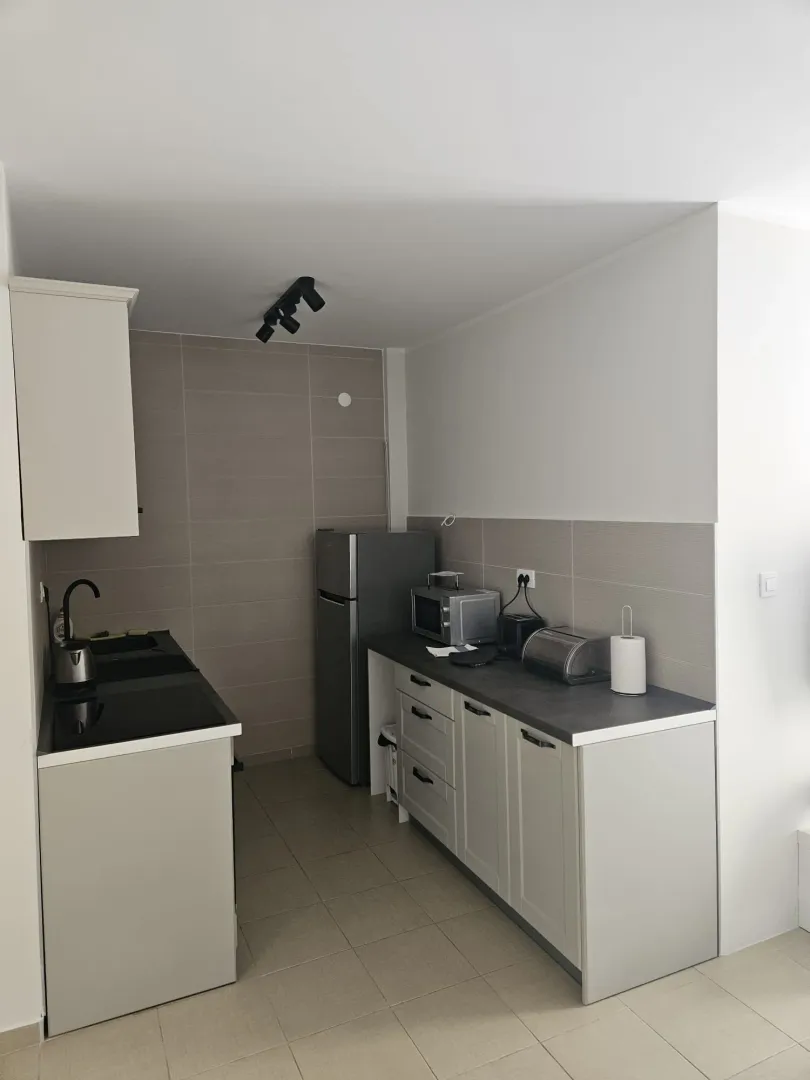 Small kitchen with light-colored cabinets, countertop, and refrigerator.