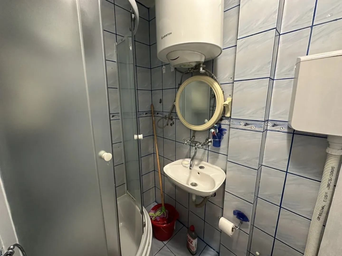 Smaller bathroom with a shower cabin, washbasin, and water heater.