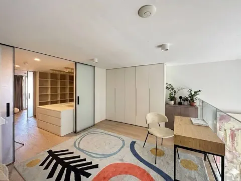 Modern bedroom with built-in wardrobe, desk, and patterned rug. - image 4