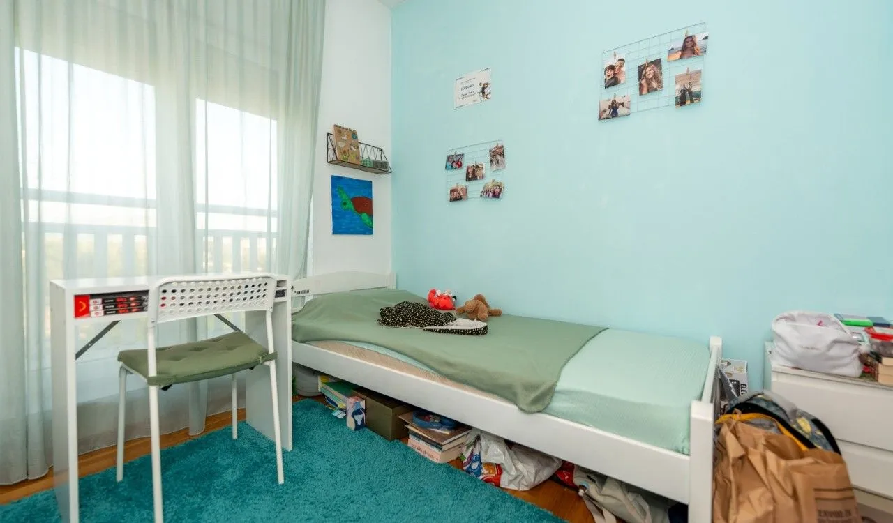 Children's bedroom with a bed, desk, and blue walls.