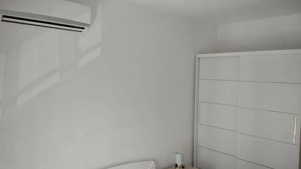 Bedroom with a white wardrobe and an air conditioning unit on the wall.