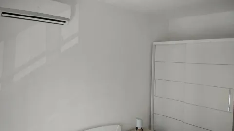 Bedroom with a white wardrobe and an air conditioning unit on the wall. - image 14
