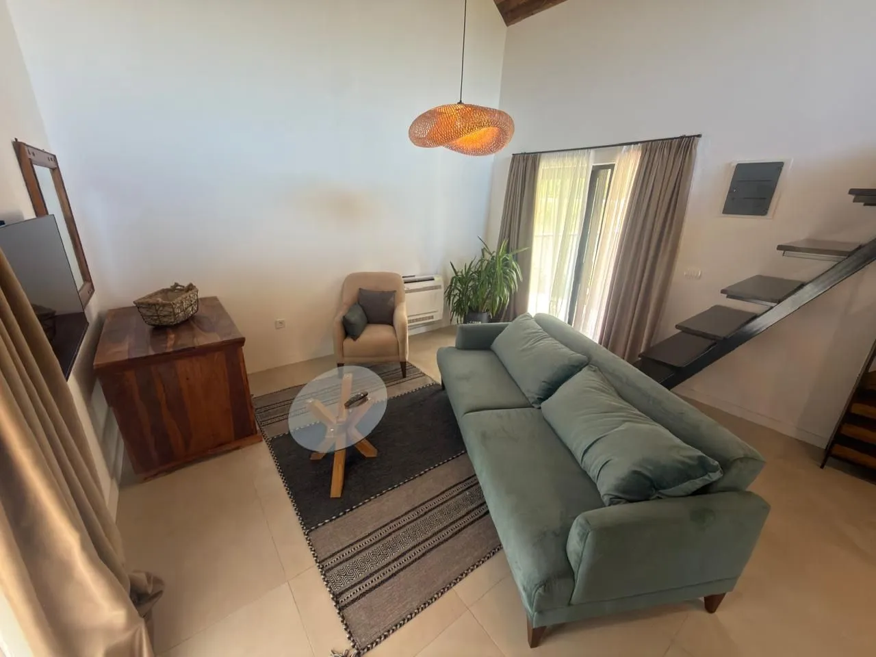 Spacious living room with sofa and stairs.