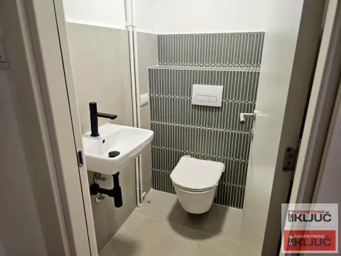 Manje kupatilo sa WC šoljom, umivaonikom i dekorativnim zelenim pločicama. - image 18