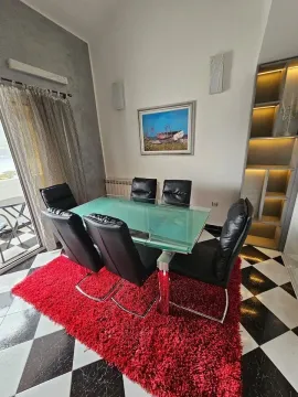 Trpezarija sa staklenim stolom, crnim stolicama i crvenim tepihom. - image 3