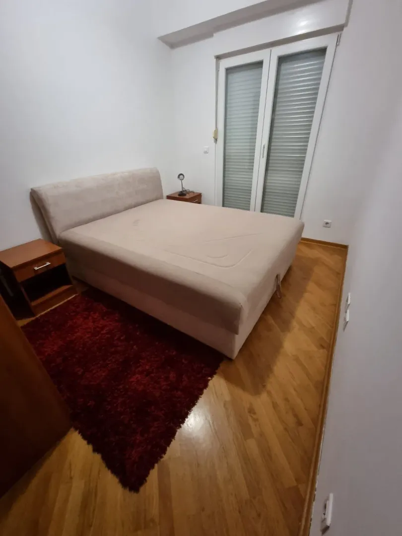Simply furnished bedroom with a double bed and wooden flooring.