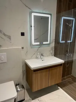 Modernly equipped bathroom with a washbasin, illuminated mirror, and walk-in shower. - image 7