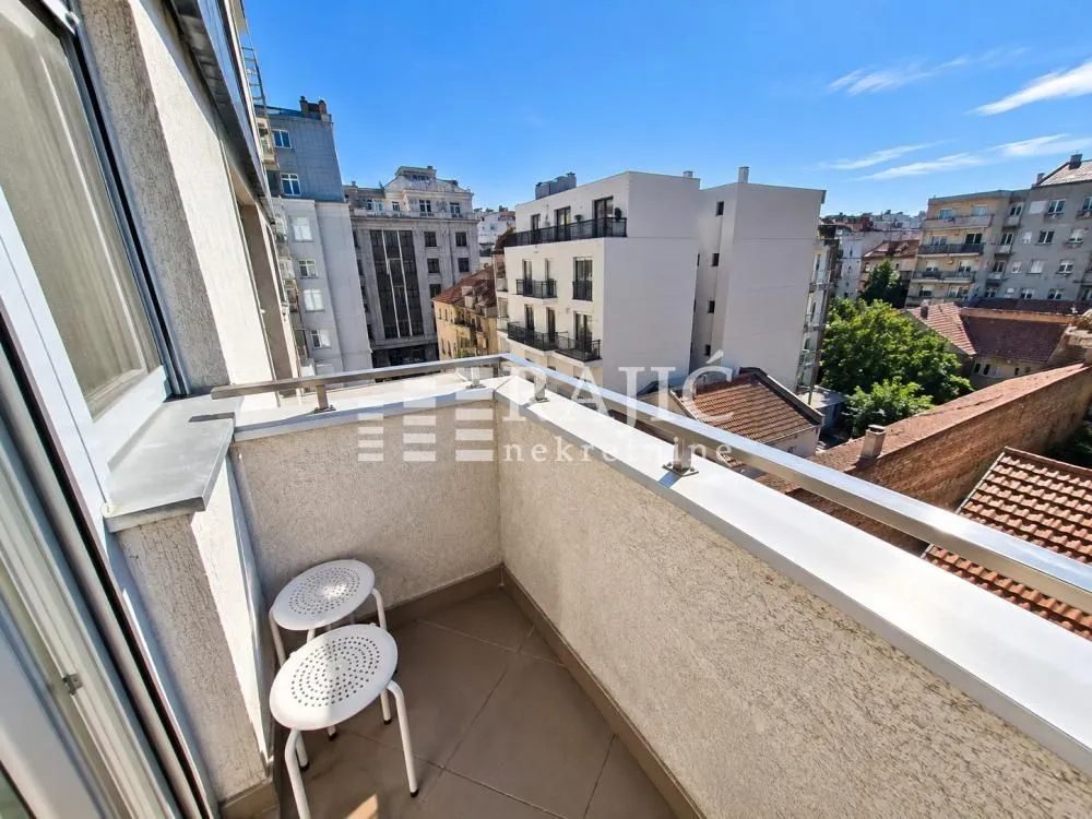 Small balcony with seating furniture and city view.