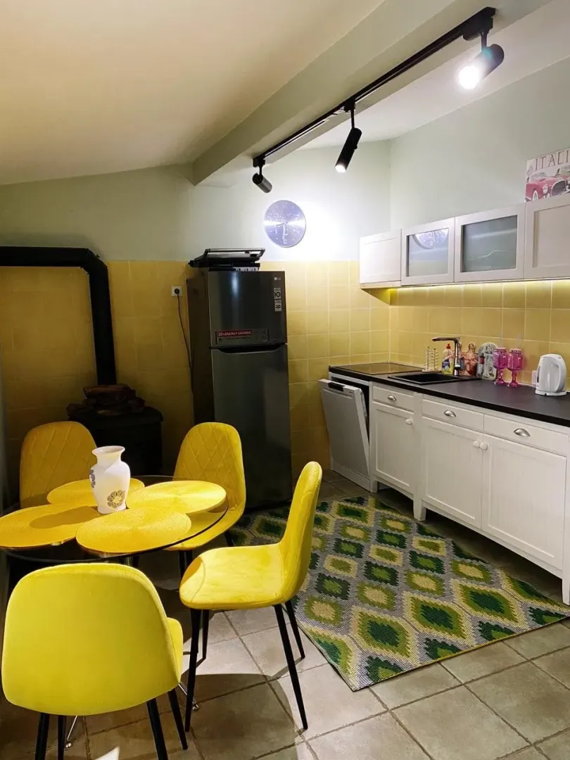Svijetla kuhinja sa trpezarijskim stolom, žutim stolicama i modernim elementima.