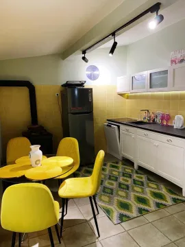 Svijetla kuhinja sa trpezarijskim stolom, žutim stolicama i modernim elementima. - image 3