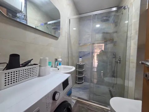 Compact bathroom with a shower cabin, sink, and washing machine. - image 10
