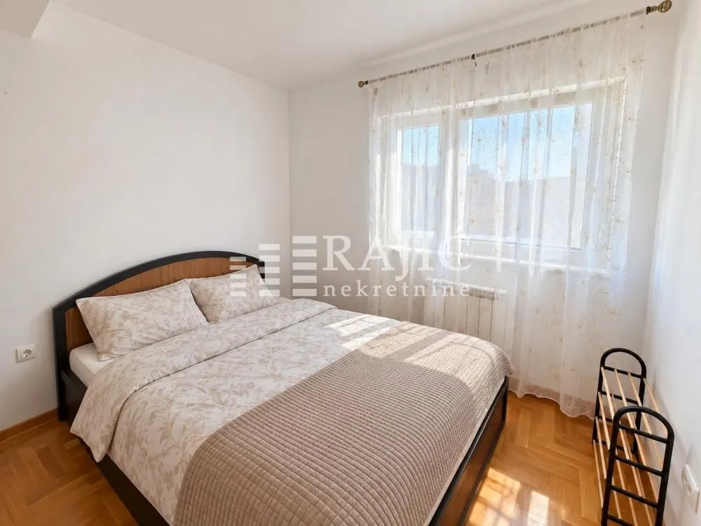 Bright and tidy bedroom with a double bed and a window.