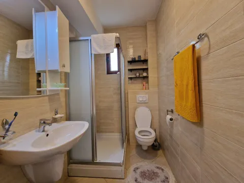 Kompaktno kupatilo sa tuš kabinom, umivaonikom i toaletom u bež tonovima. - image 6