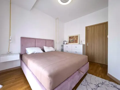 Spavaća soba sa bračnim krevetom, komodom i drvenim podom. - image 12