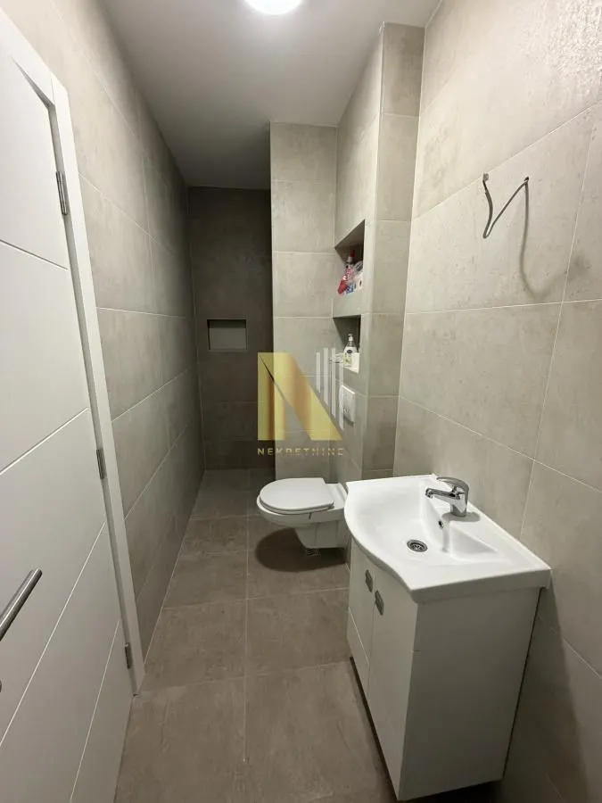 Modern bathroom with a sink, toilet, and tiled shower area.
