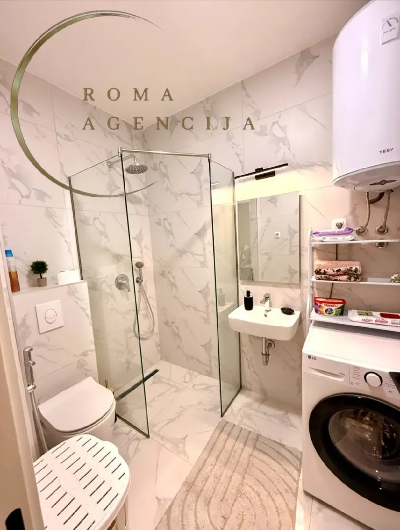 Smaller bathroom with a walk-in shower, washbasin, and washing machine.