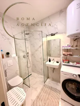 Smaller bathroom with a walk-in shower, washbasin, and washing machine. - image 8
