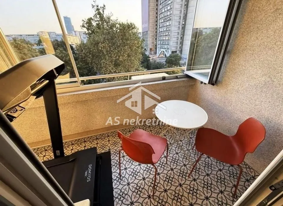 Natkriveni balkon sa garniturom za sedenje i pogledom na grad.