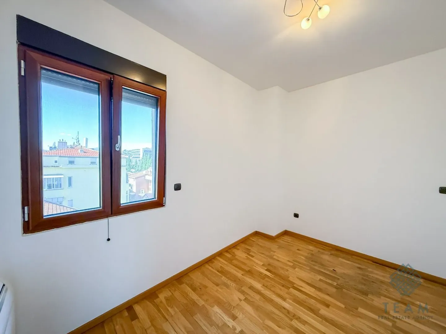 Empty room with white walls, wooden floor and a window.