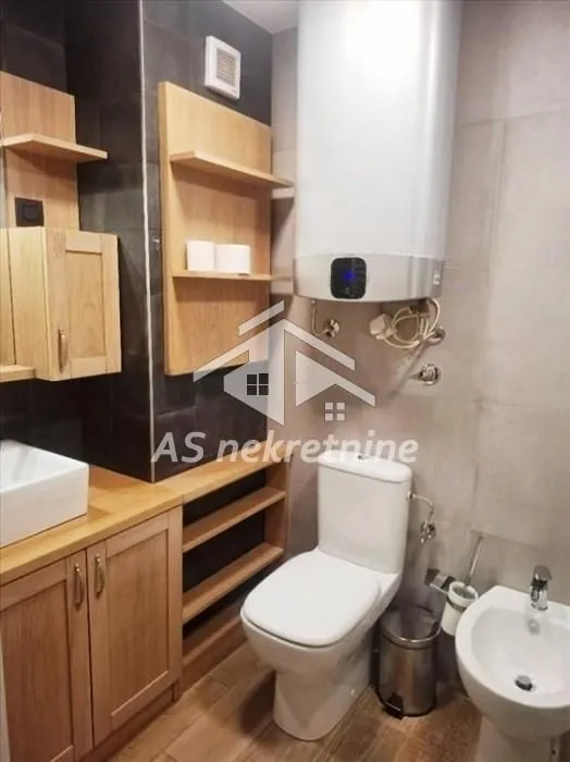 Manje kupatilo sa wc šoljom, bideom, umivaonikom i bojlerom.
