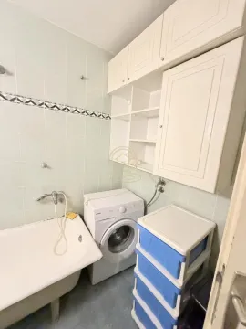 Kupatilo opremljeno kadom, veš mašinom i belim zidnim elementima. - image 17