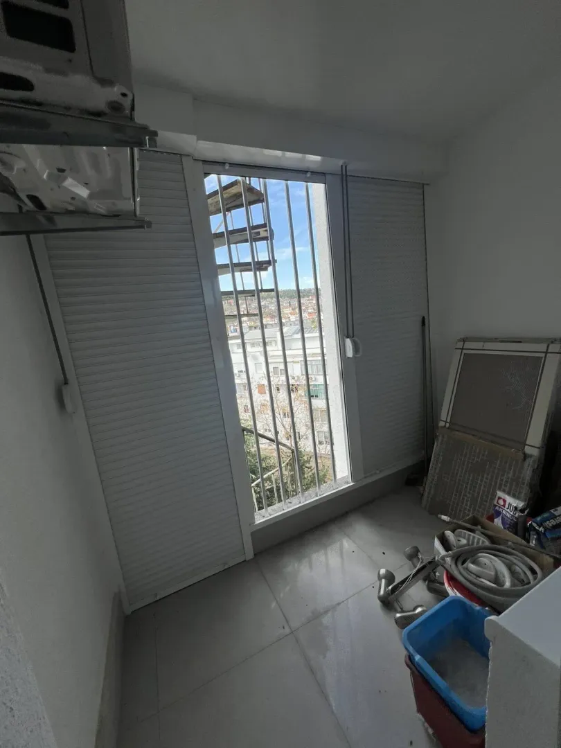 Enclosed balcony with security bars and construction materials.