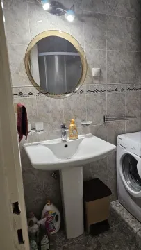 Bathroom with a sink, mirror, shower cabin, and washing machine. - image 11