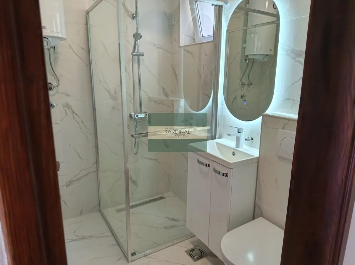 Moderno kupatilo sa tuš kabinom, umivaonikom i wc šoljom.