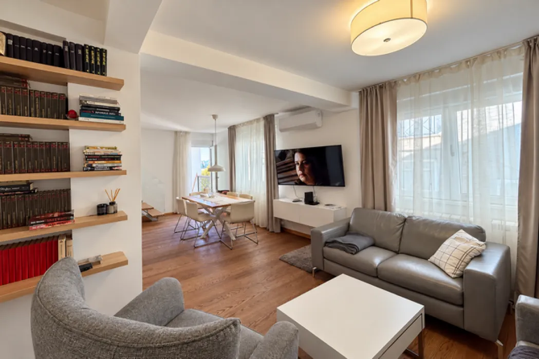 Living room with a sofa, TV, and a dining area in the background.