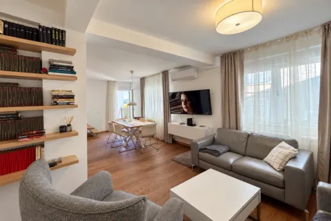 Living room with a sofa, TV, and a dining area in the background. - image 21