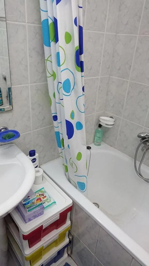 Smaller bathroom with a bathtub, shower curtain, and washbasin.