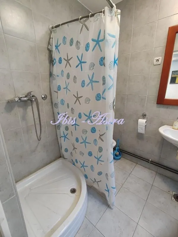Bathroom with a shower cabin, washbasin, and tiled walls.