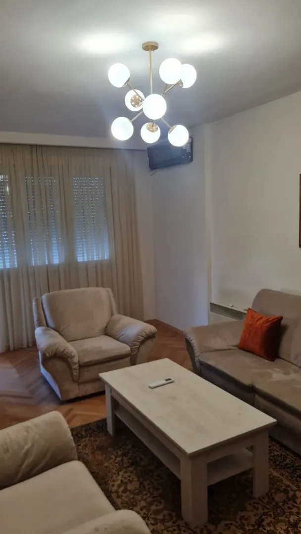 Svijetla dnevna soba sa udobnim namještajem i modernim lusterom.