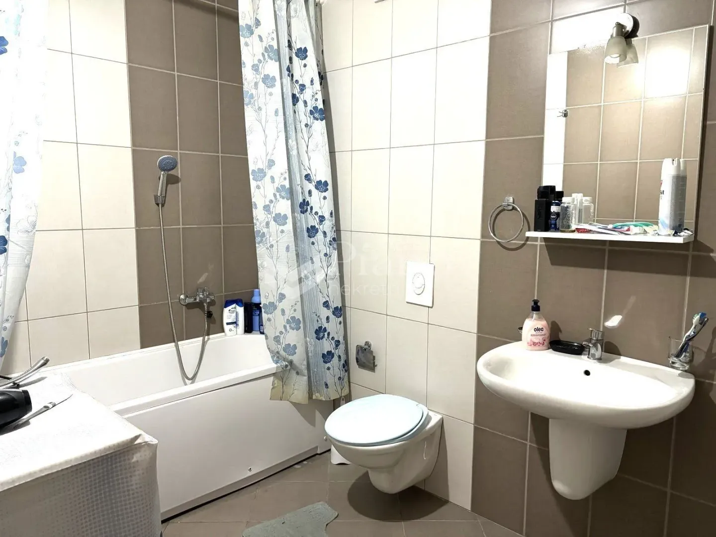 Smaller bathroom with a bathtub, washbasin, toilet, and mirror.