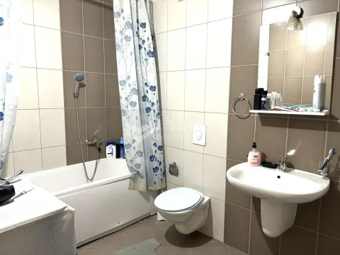 Smaller bathroom with a bathtub, washbasin, toilet, and mirror. - image 5