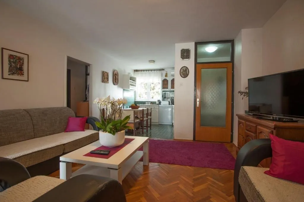 Living room with sofa, coffee table, and television, with a view of the dining area.