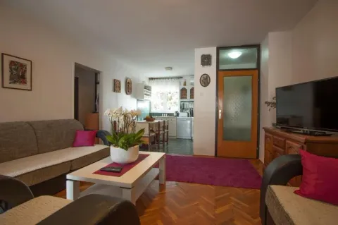 Living room with sofa, coffee table, and television, with a view of the dining area. - image 4