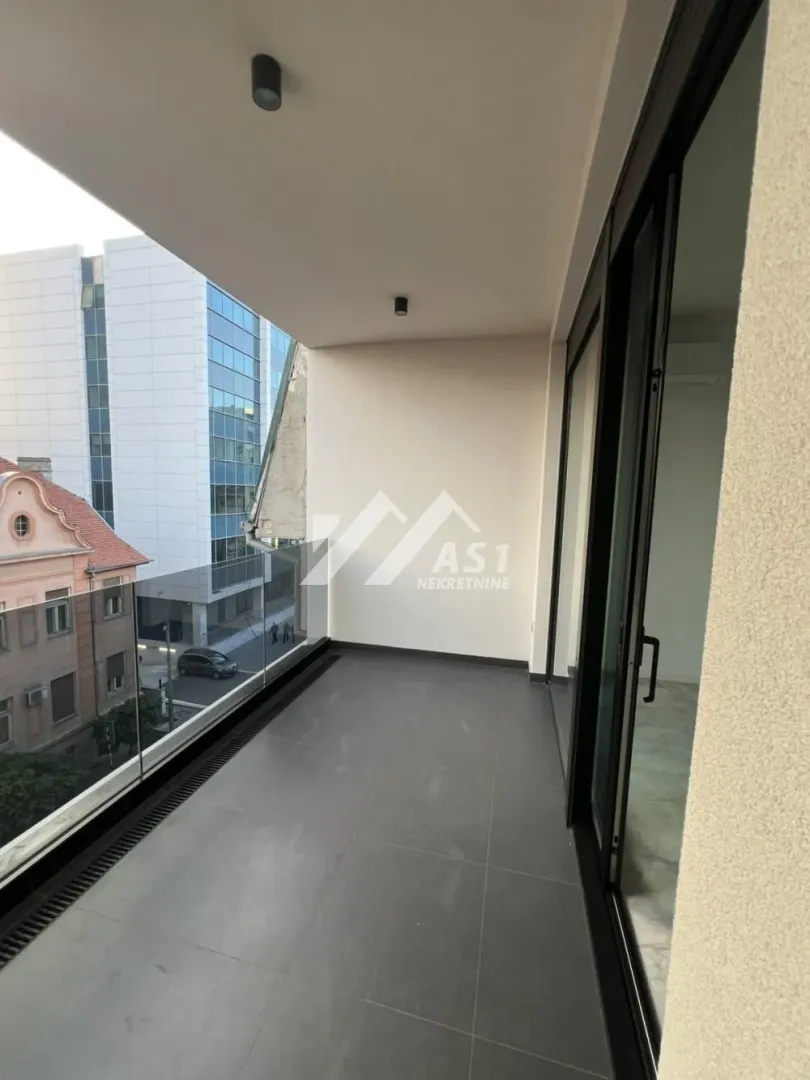 Covered balcony with dark tiles and a glass railing.