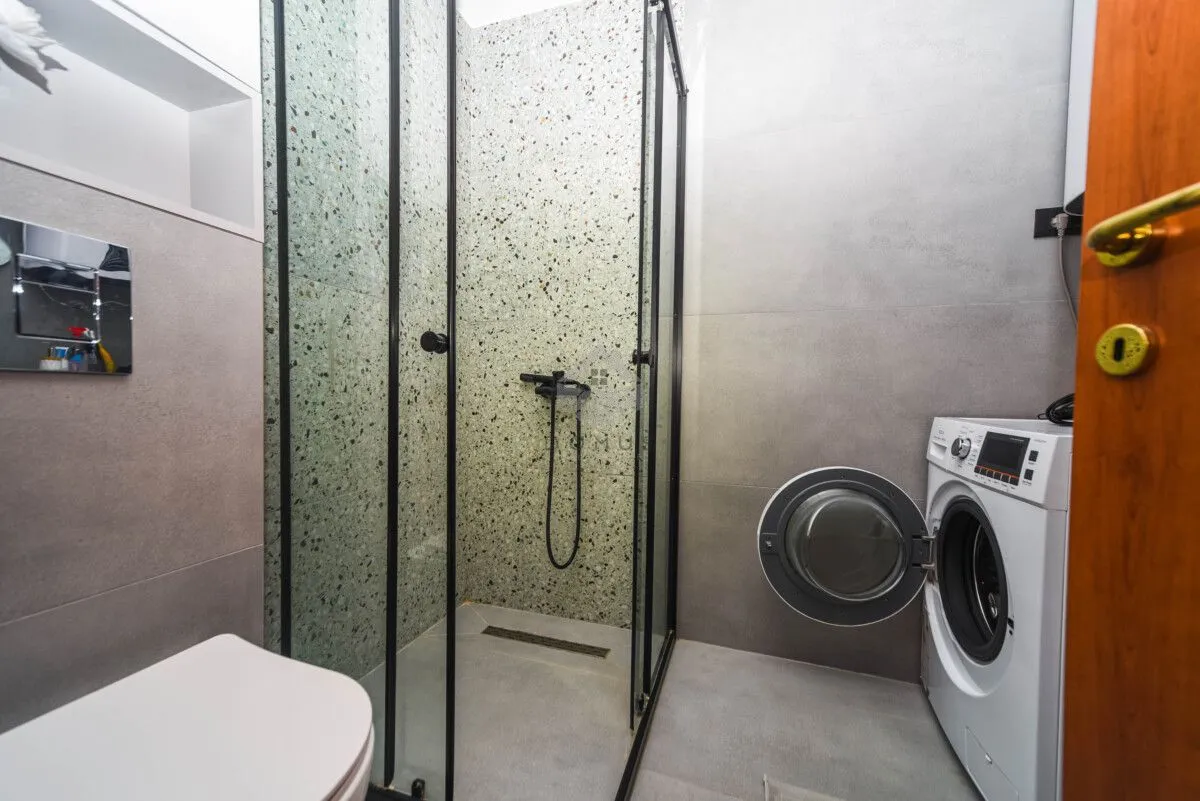 Modern bathroom with a walk-in shower and washing machine.