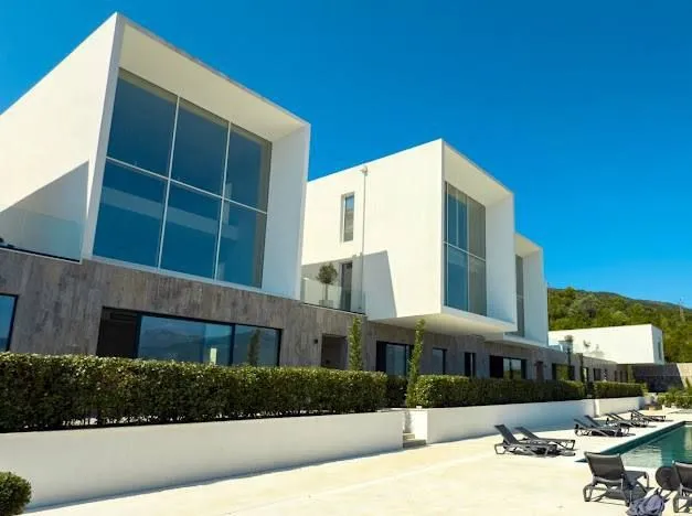 Spoljašnji izgled moderne zgrade sa bazenom i ležaljkama.