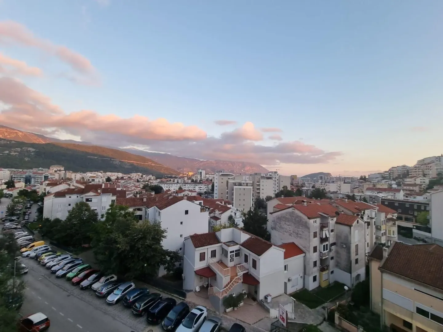 Pogled sa terase na grad i okolne planine u suton.