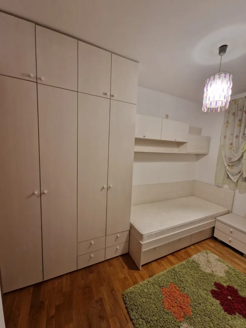 Svijetla dječija soba sa velikim ugradnim plakarom i jednokrevetnim ležajem.