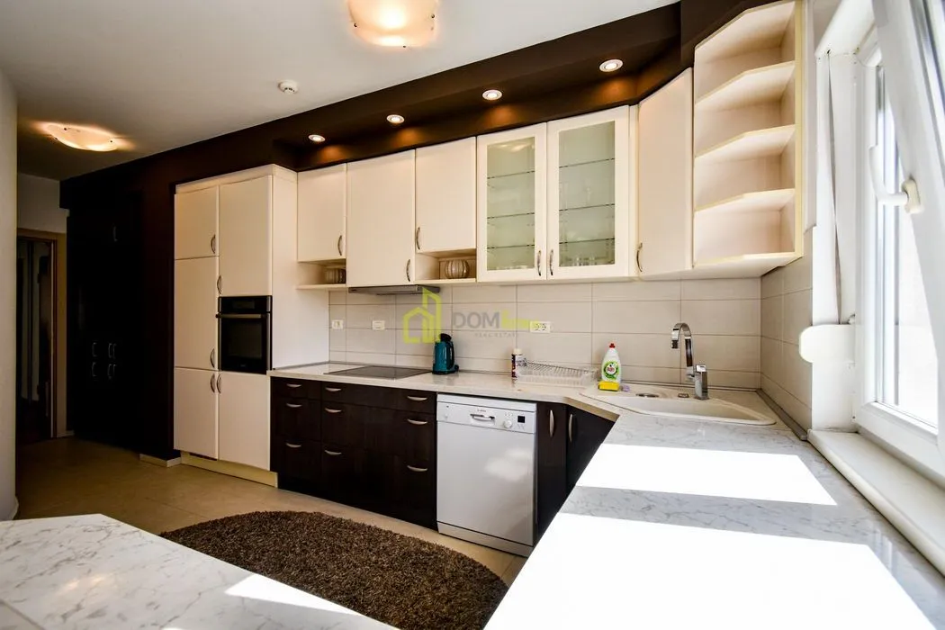Kitchen with light upper and dark lower cabinets, built-in appliances, and a sink under the window.
