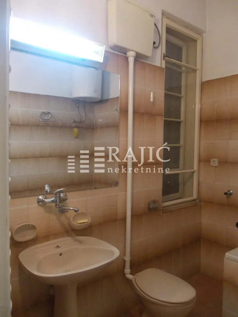 Older equipped bathroom with a sink and toilet.