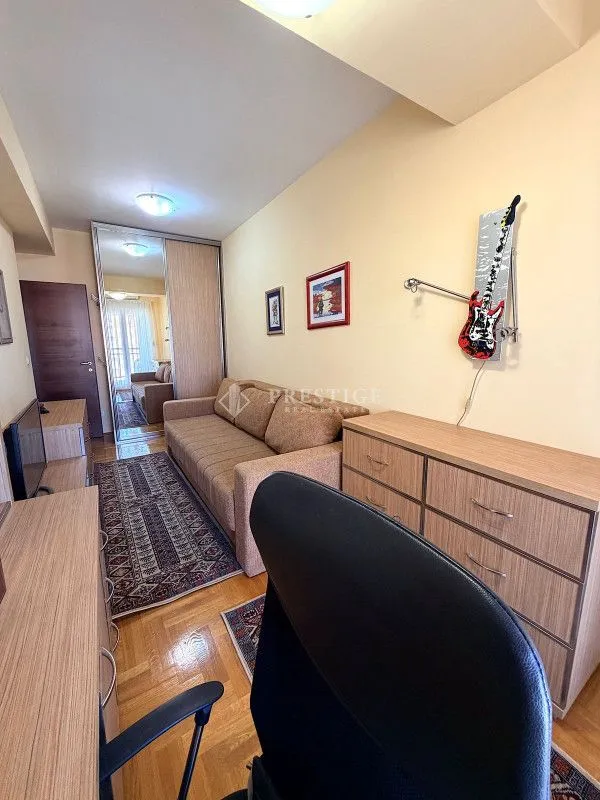Living room furnished with a sofa, dresser, and office desk.